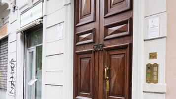 Una puerta doble de madera con un picaporte de latón, una placa con un número y una pequeña señal encima.