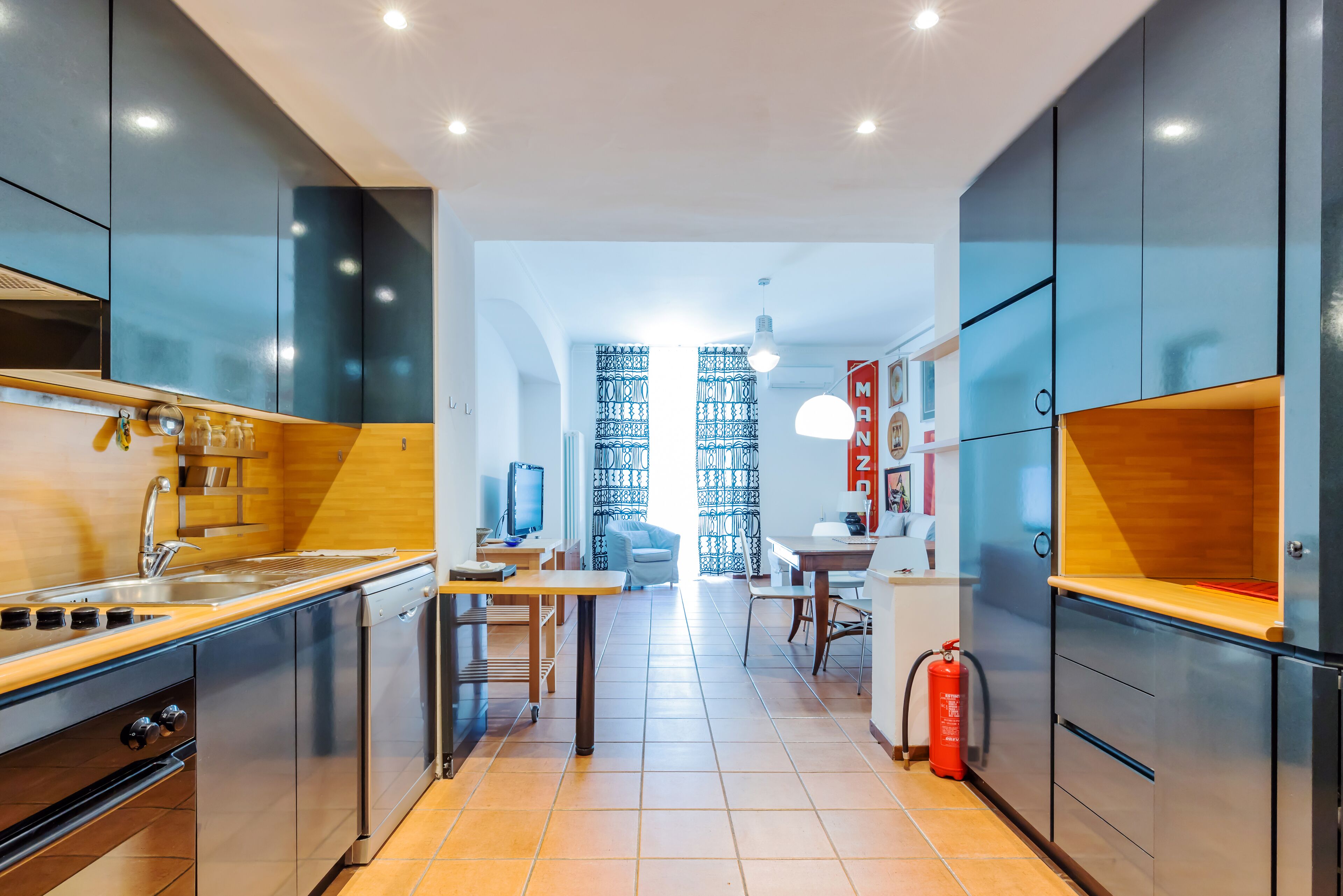 A modern kitchen with stainless steel appliances, a wooden countertop, and a dining area with a table and chairs.