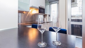 A modern kitchen with a dark countertop, two wine glasses, and a view of the city through a window. - Milan Retreats - Central Station (Milan)