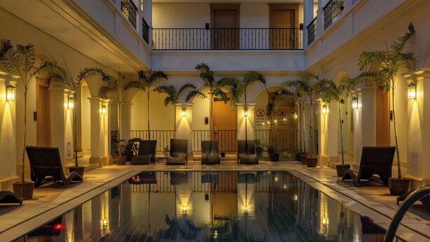 A multi-level indoor swimming pool with a tiled floor, surrounded by lounge chairs and potted plants. - Boracay Sands Hotel (Boracay Island)