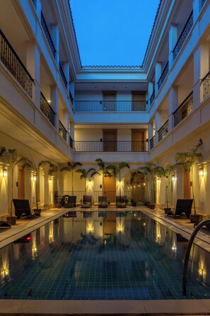 A multi-level indoor swimming pool with a tiled floor, surrounded by lounge chairs and potted plants. - Boracay Sands Hotel (Boracay Island)