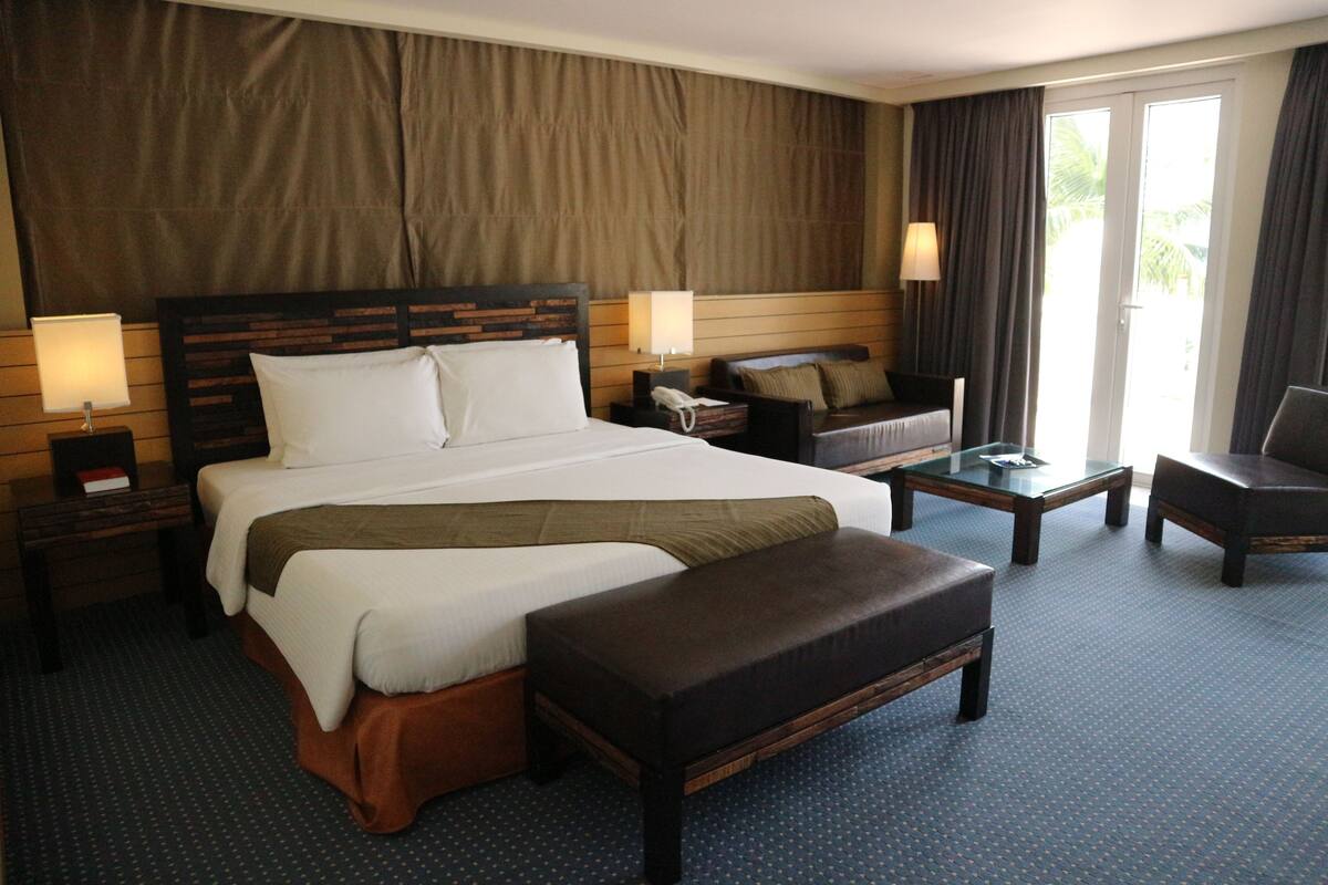Habitación de hotel con una cama grande, un sofá, una mesa de centro y un escritorio.