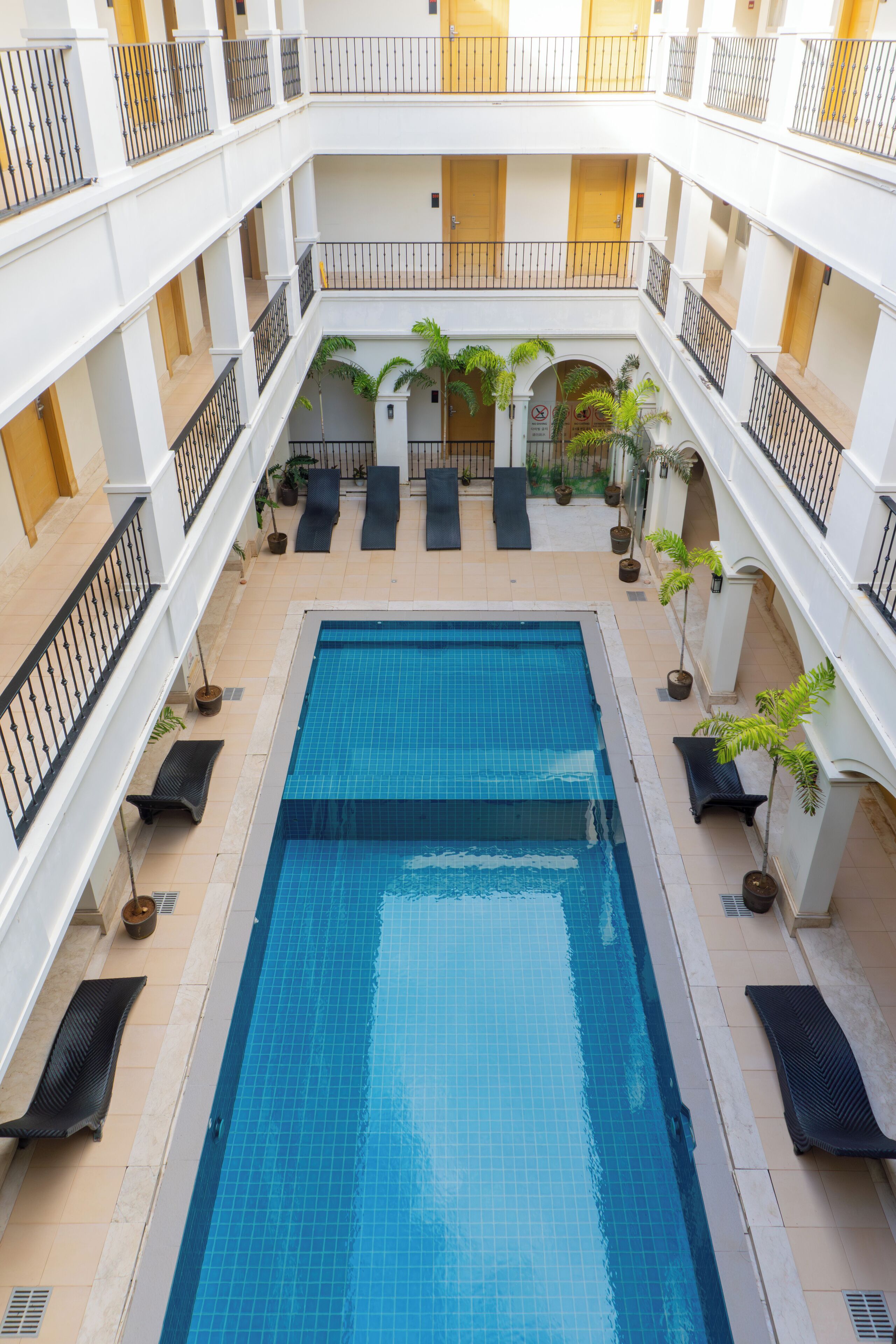 En poolanläggning inomhus med flera nivåer, kaklade väggar och ett centralt poolområde.