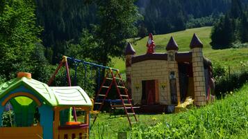 Children can play in the charming outdoor play area featuring a colorful playhouse and a small building with a mural.