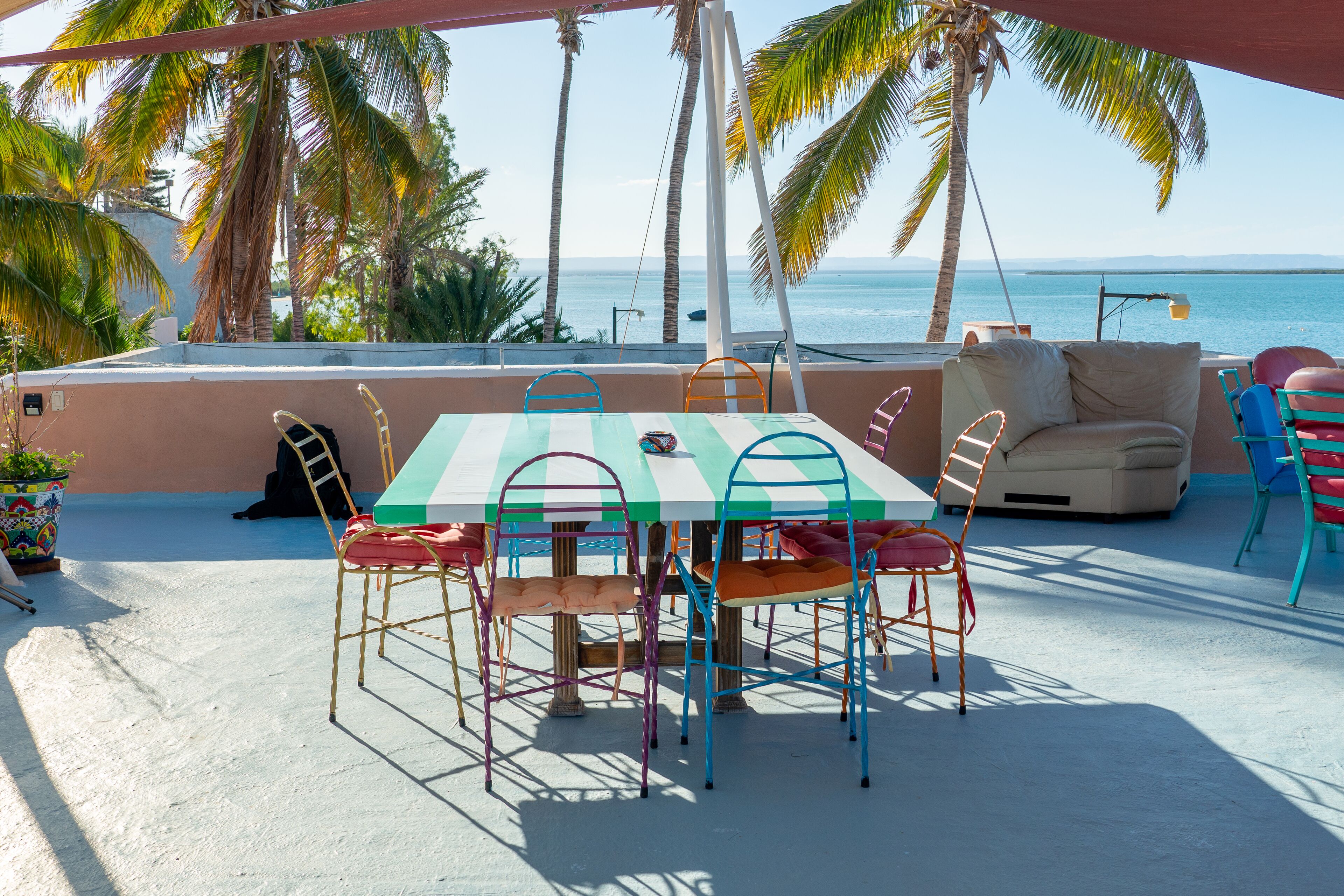 A patio with a table and chairs, a sofa, and a view of the ocean.