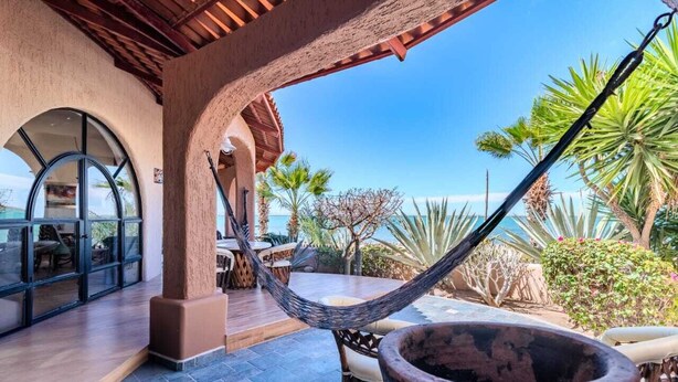 A covered outdoor area with a hammock, a large pot, and a view of the ocean. - Casa Kootenay Waterfront BnB (La Paz)