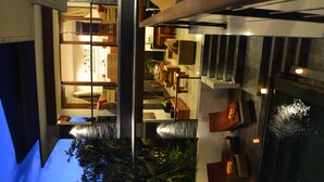 A modern hotel interior with a staircase connecting two floors, a dining area, and a pool area. - Villa Lea (Tabanan)