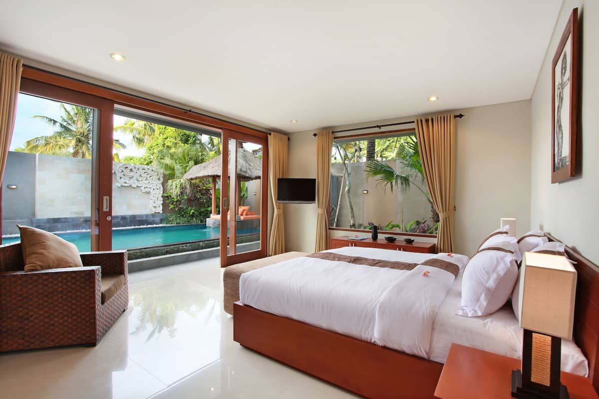 Quarto com cama grande, televisão e vista para uma piscina.