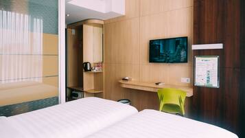 Een hotelkamer met een bed, een bureau met een stoel, een televisie en een spiegel.
