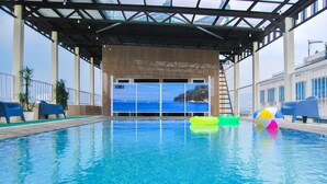 A swimming pool with clear blue water, surrounded by blue chairs and a colorful ball. - Tebu Hotel Bandung (Bandung)