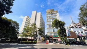 A modern urban street with tall buildings, a clear sky, and a variety of shops and restaurants. - Tebu Hotel Bandung (Bandung)
