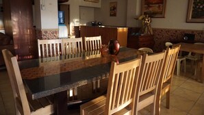 Un comedor con una mesa larga, sillas de madera y un dispensador de agua.