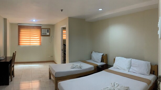 Habitación de hotel con dos camas, un escritorio y una ventana con persianas.