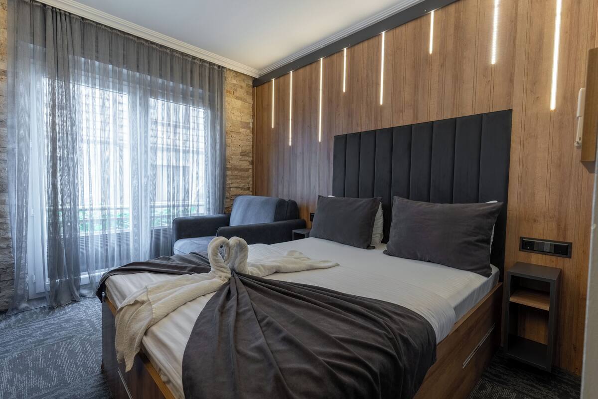 Una habitación de hotel moderna con una cama grande, una mesita de noche y un espacio para sentarse.