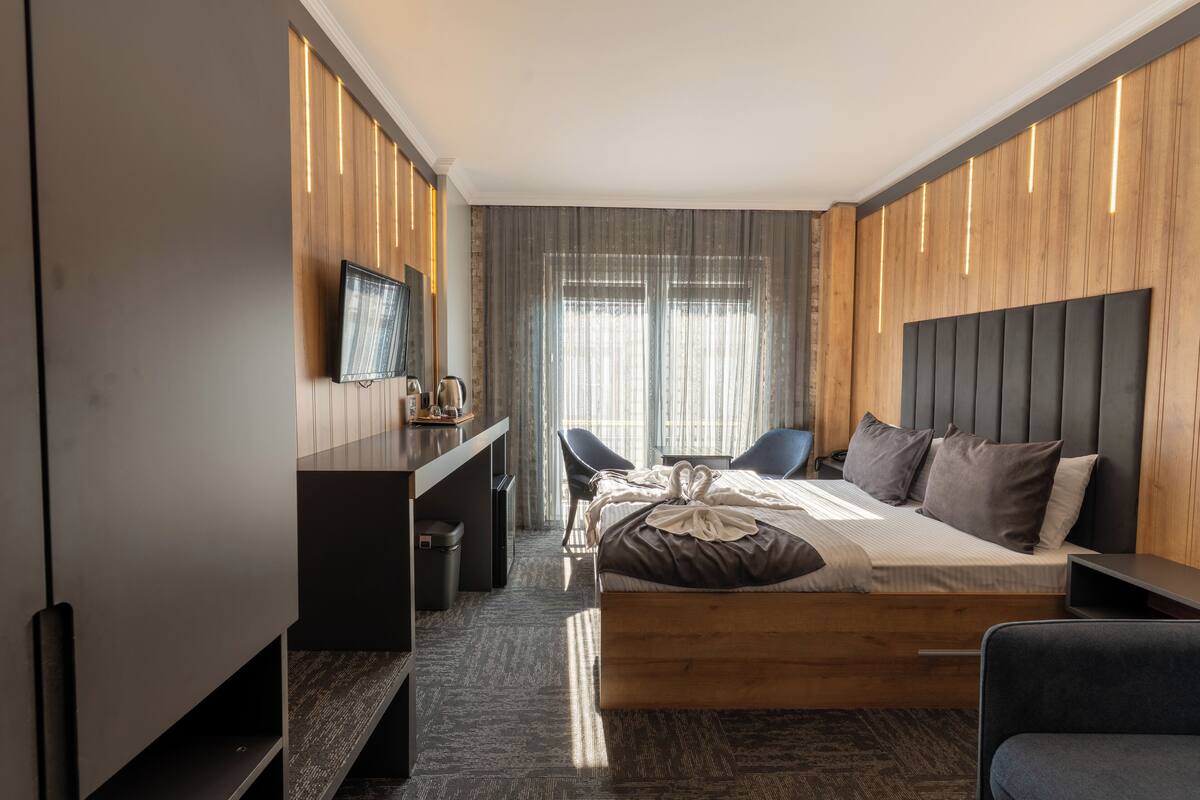 Una habitación de hotel moderna con una cama grande, un escritorio, una silla y un televisor.
