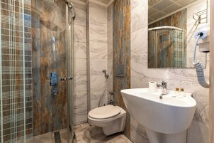 Un baño moderno con ducha de vidrio, inodoro blanco y lavamanos con espejo.