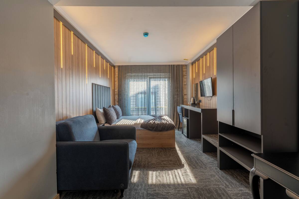 Una habitación de hotel moderna con sofá, cama, televisión y escritorio.