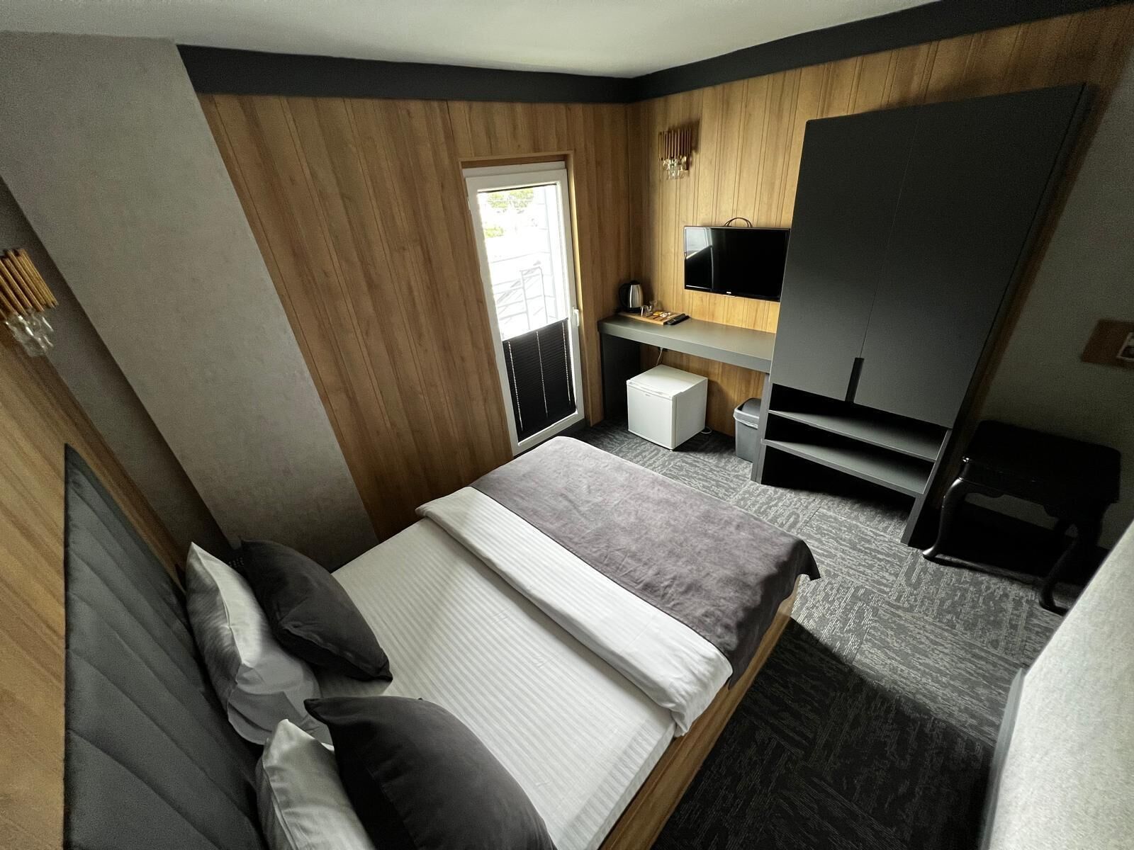 Une chambre à coucher comprenant un lit, une table de chevet, un bureau avec une chaise, une télévision et une armoire.