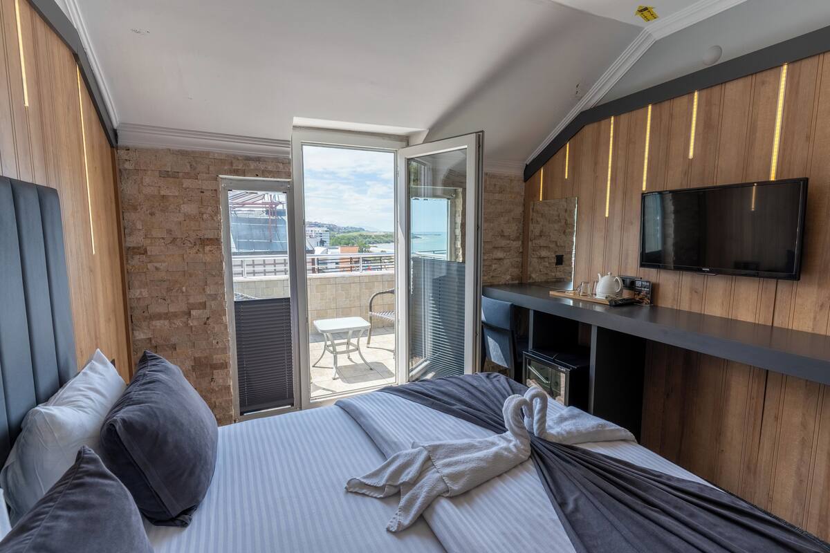 Una habitación de hotel moderna con una cama grande, un televisor y un balcón con vistas a la ciudad.