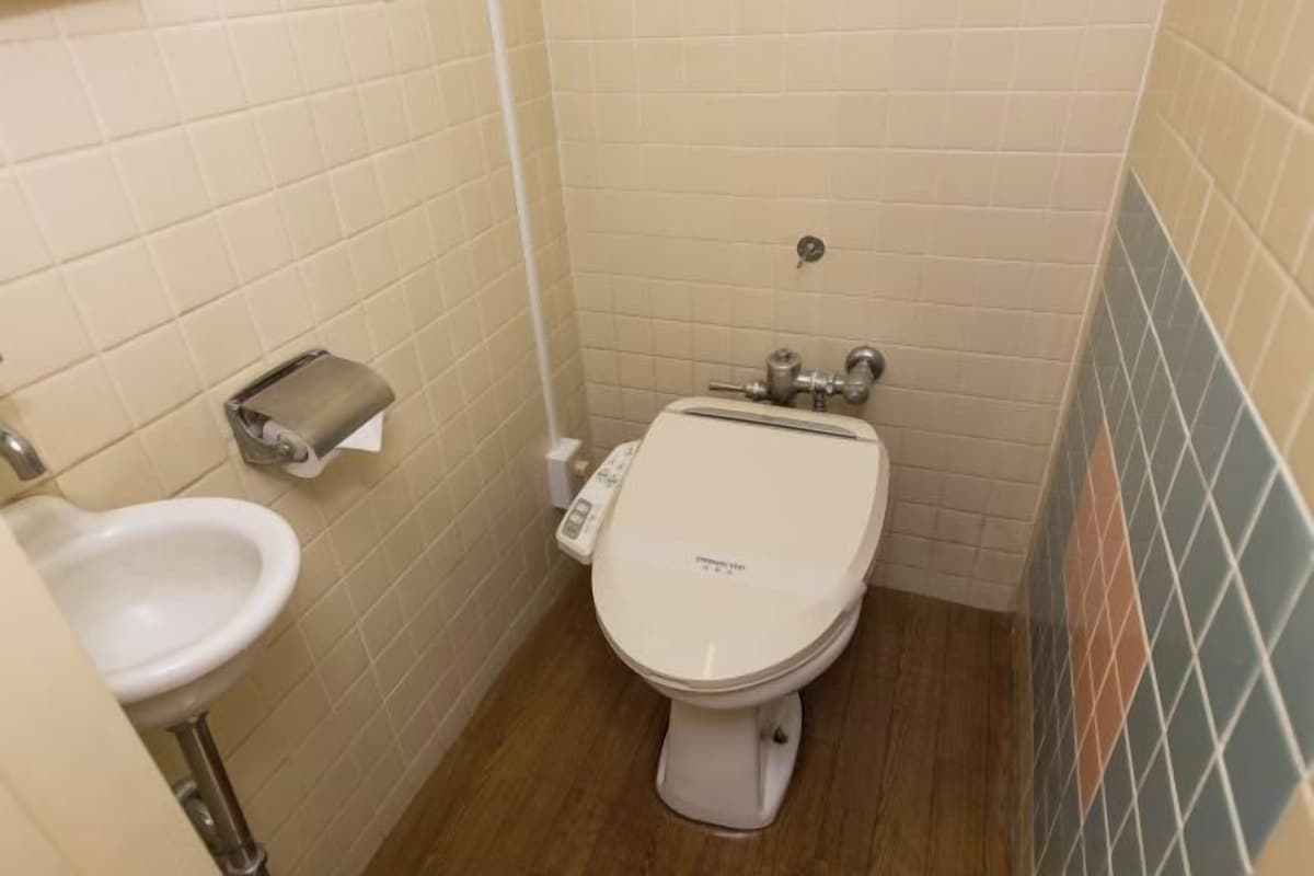 Une petite salle de bain équipée de toilettes, d’un lavabo et d’un distributeur de serviettes en papier.