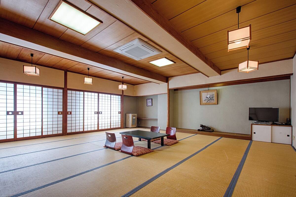 Una habitación japonesa tradicional con suelo de tatami, una mesa baja y puertas correderas.
