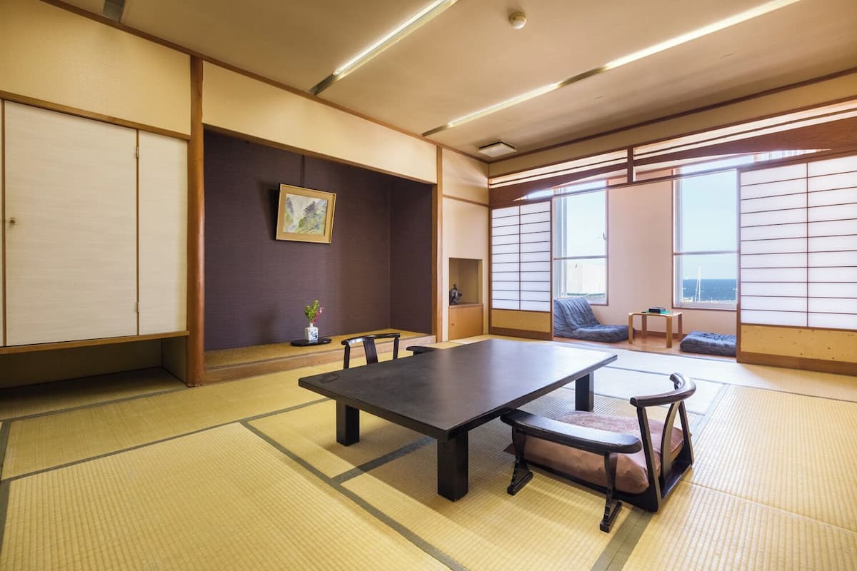 Una habitación japonesa tradicional con suelo de tatami, una mesa baja y puertas correderas.