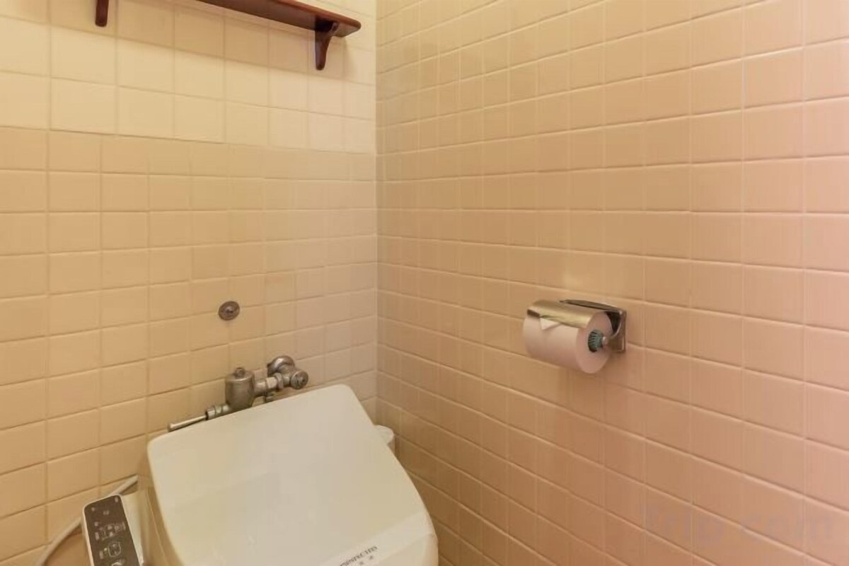 A bathroom with a toilet, a hand dryer, and a paper towel dispenser.