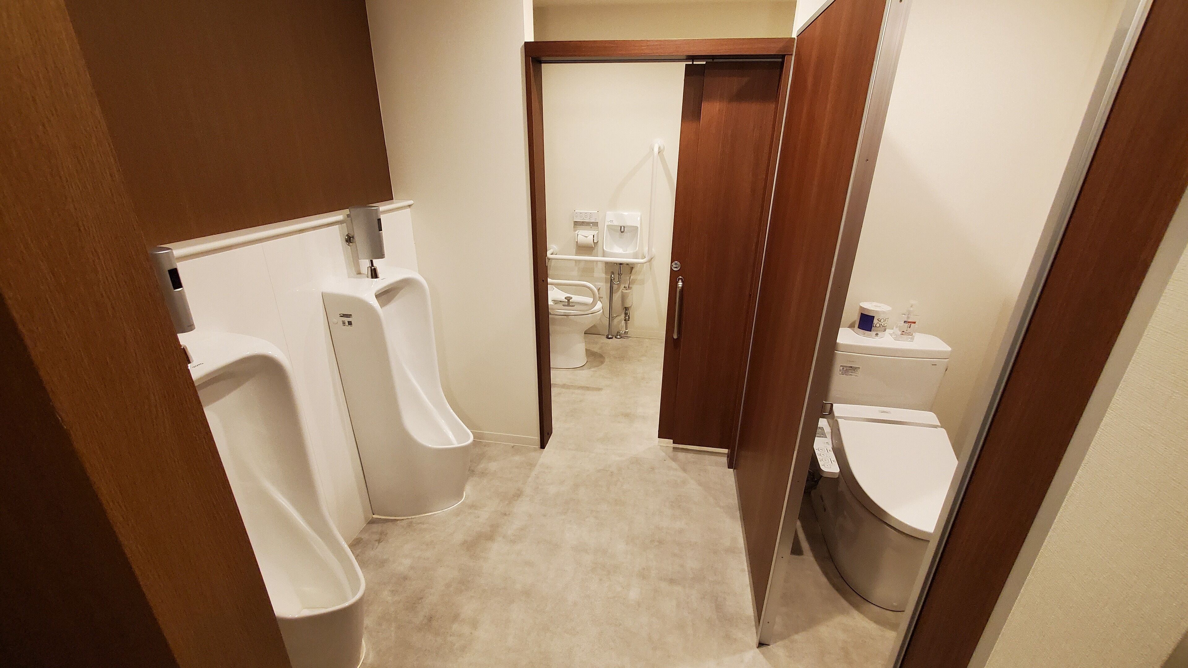Baño de hombres con orinales, un inodoro y un secamanos.