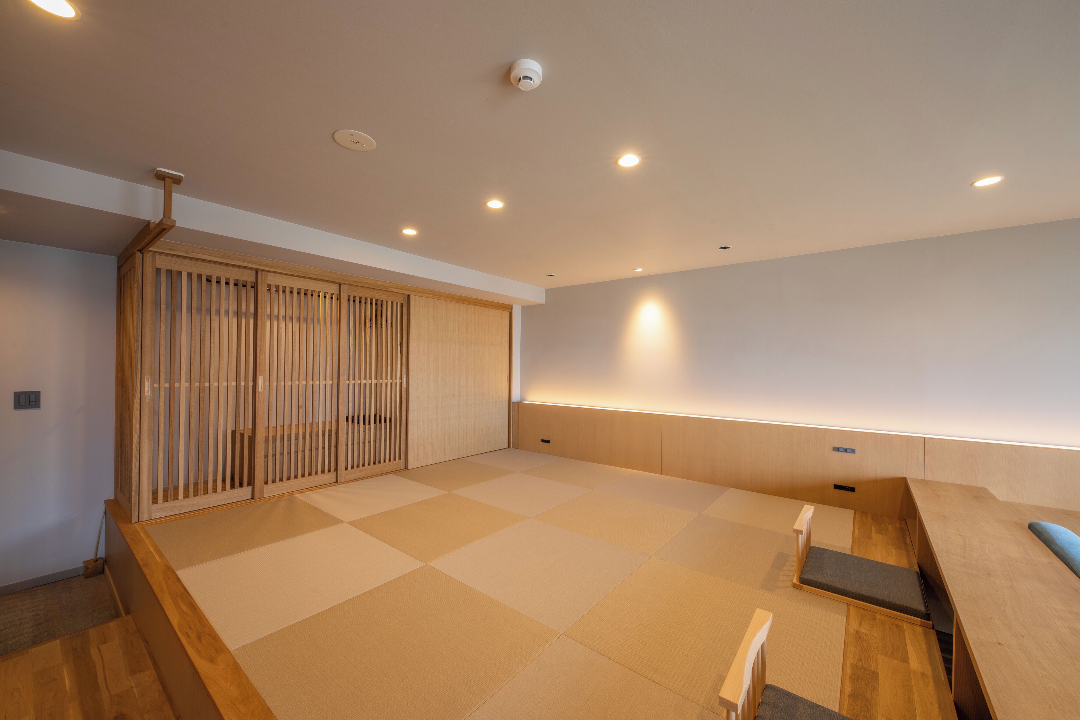 A modern interior with tatami flooring, a sliding door, and a low wooden bench.