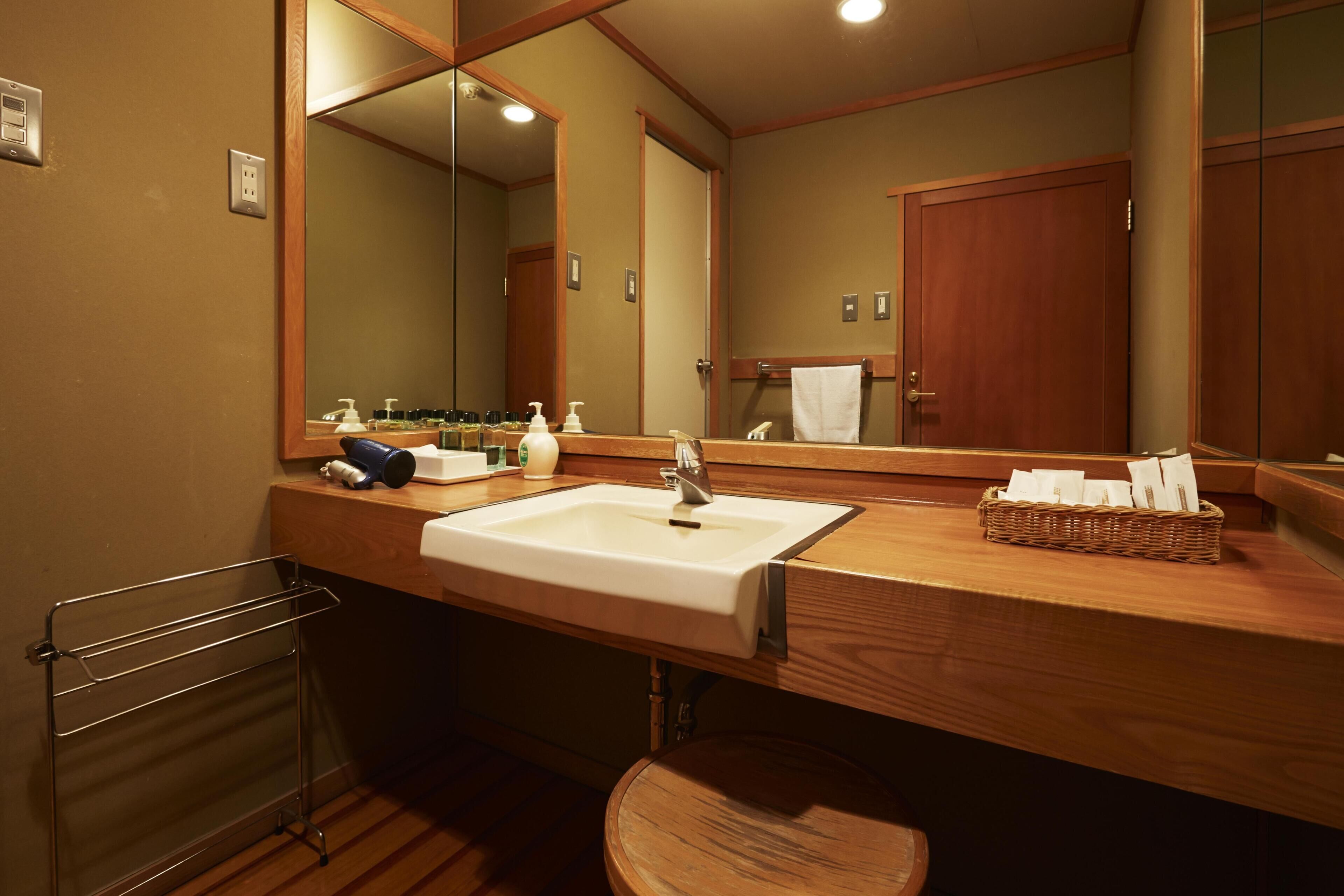 A bathroom with a wooden vanity, a white sink, a mirror, and a towel rack.