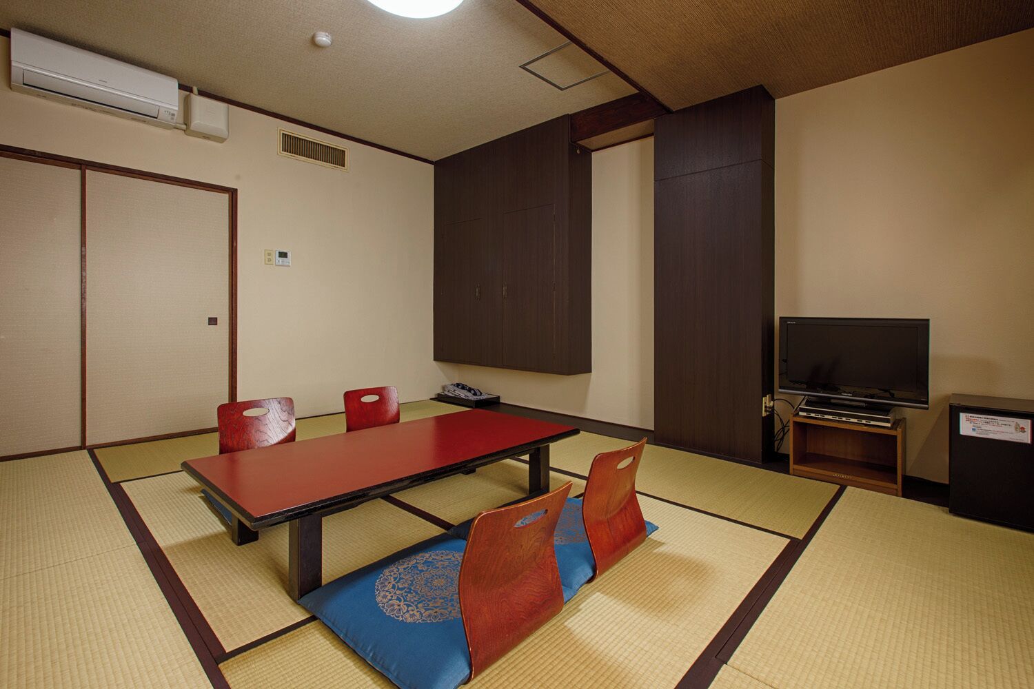 Een traditionele Japanse kamer met tatami vloeren, een lage tafel en rode kussens.