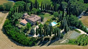 Vista aérea de una propiedad con una casa principal, una piscina y follaje circundante.