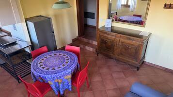 Un coin repas avec une table ronde, des chaises rouges, un buffet en bois et un miroir au mur.