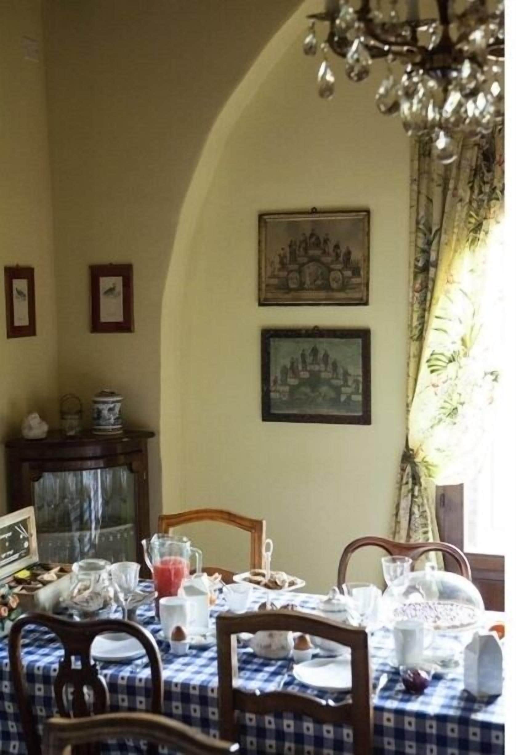 A dining area with a table set for four, framed pictures on the wall, and a chandelier above.
