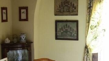 A dining area with a table set for four, framed pictures on the wall, and a chandelier above.