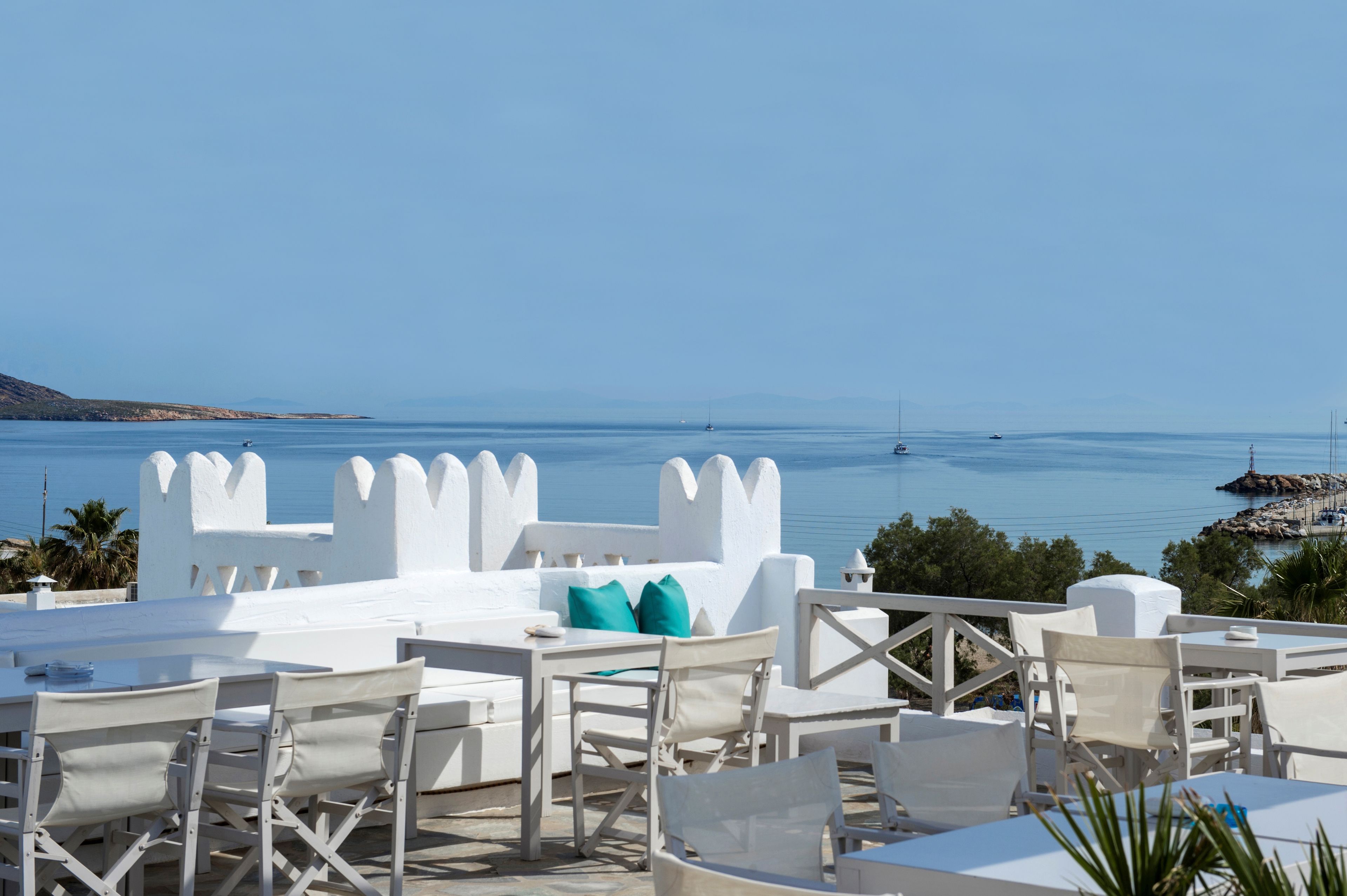 Una terraza frente al mar con muebles blancos y vistas al océano.