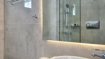 Un baño moderno con un espejo grande, un lavabo redondo y una cabina de ducha de cristal.