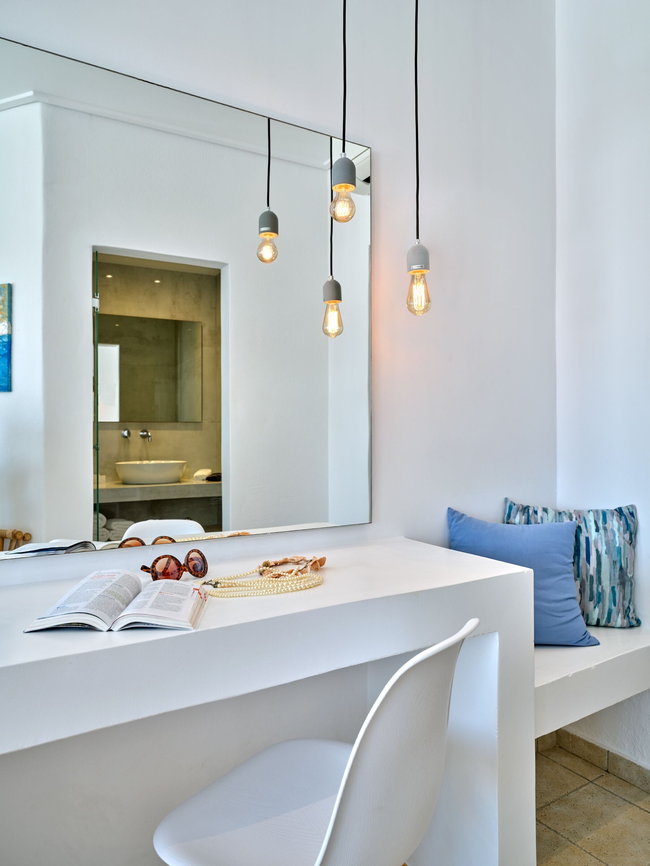 A modern bathroom with a white vanity, a large mirror, and a hanging light fixture.
