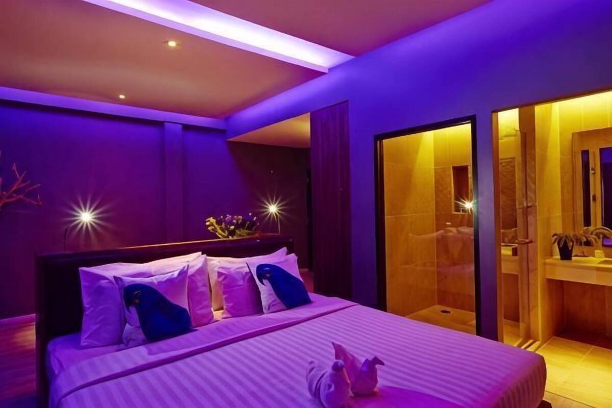 Un dormitorio moderno con una cama grande, un ventanal de vidrio que da a un baño y una zona de ducha visible.