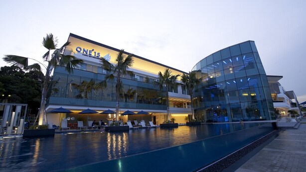 A modern hotel with a pool, palm trees, and a glass facade. - ONE15 Marina Hotel Sentosa Cove (Singapore)