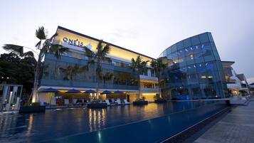 Relax by the pool with lounge chairs and umbrellas, surrounded by palm trees and a rooftop terrace.