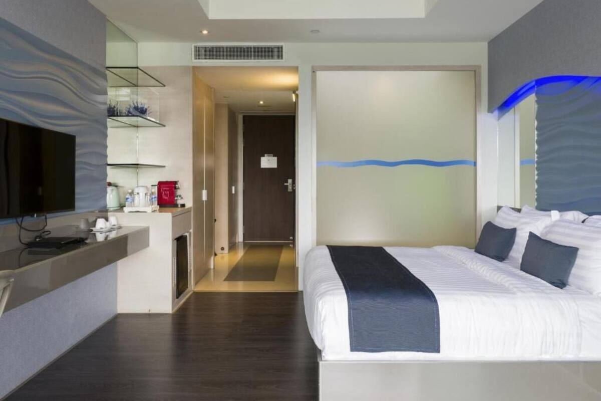 Une chambre d’hôtel moderne équipée d’un lit, d’un bureau et d’une télévision.