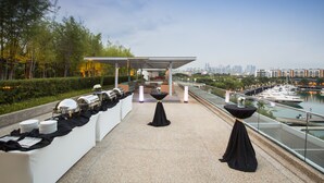 An outdoor dining area with a view of a marina and city skyline. - ONE15 Marina Hotel Sentosa Cove (Singapore)