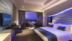 A modern hotel room with a large bed, a desk, and a TV displaying the hotel's name. - ONE15 Marina Hotel Sentosa Cove (Singapore)