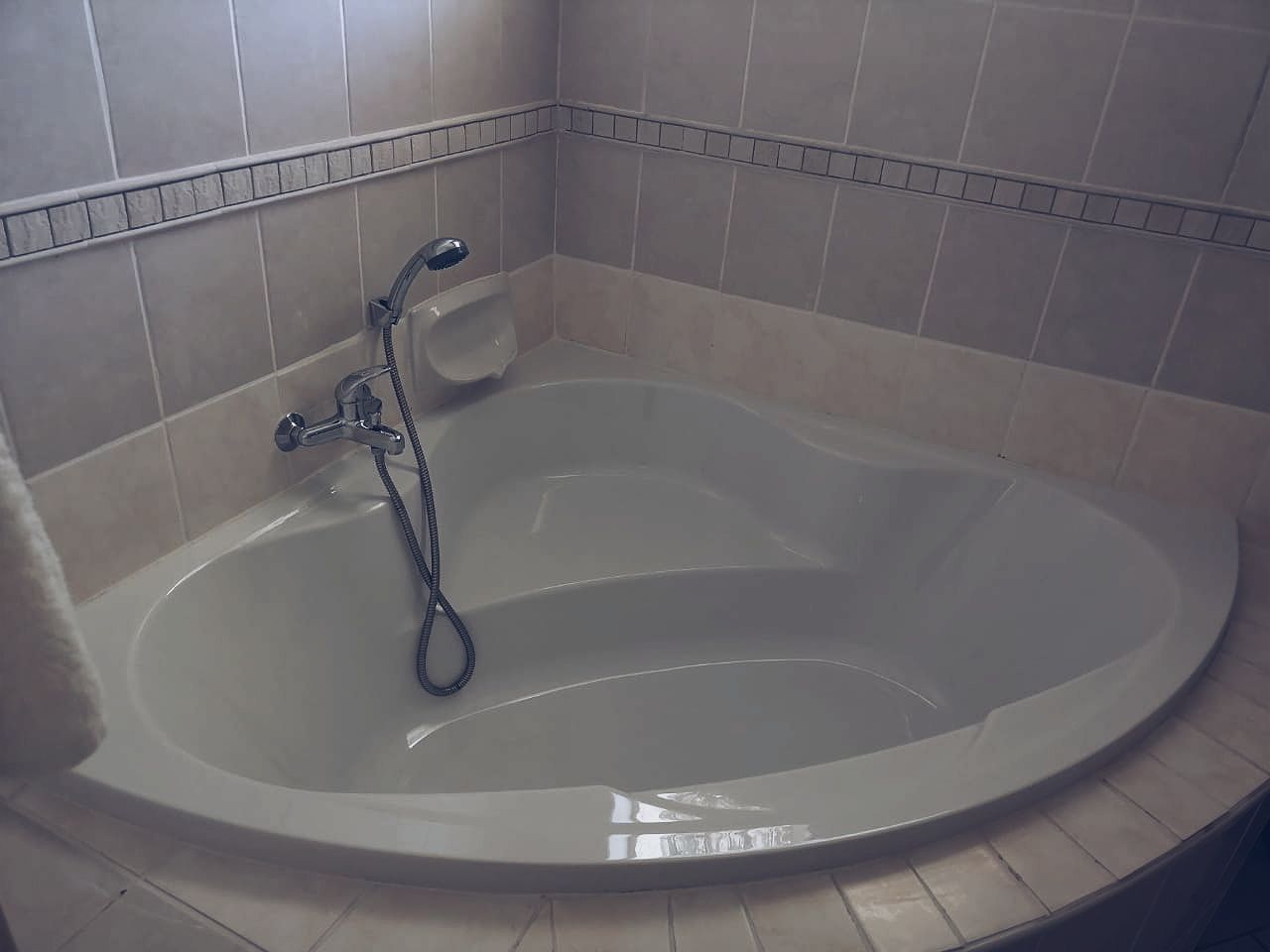 Un baño con una bañera grande, un cabezal de ducha y un perchero para toallas.