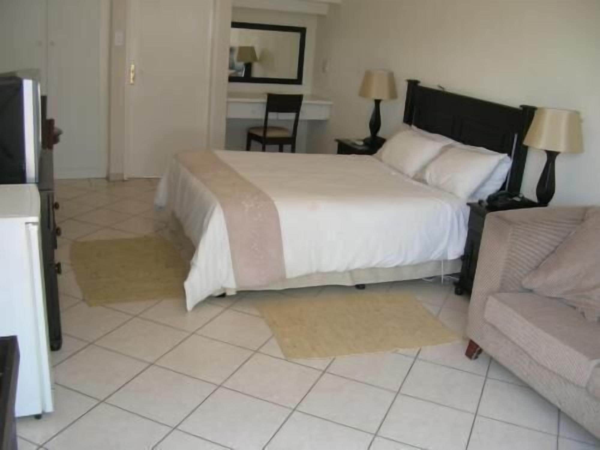 A hotel room with a bed, a desk, a chair, and a sofa.