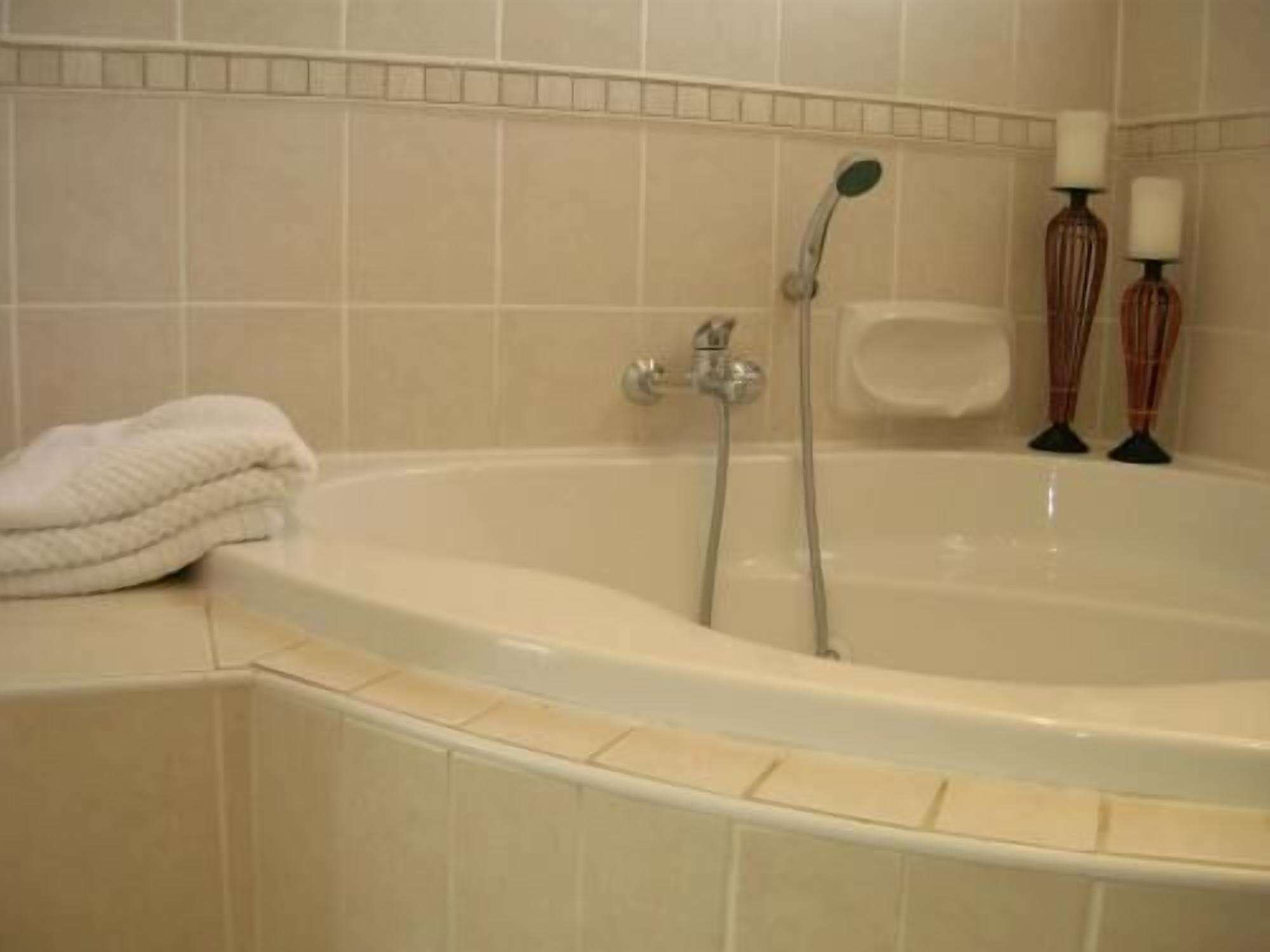 Un baño con una bañera, una toalla y dos velas.