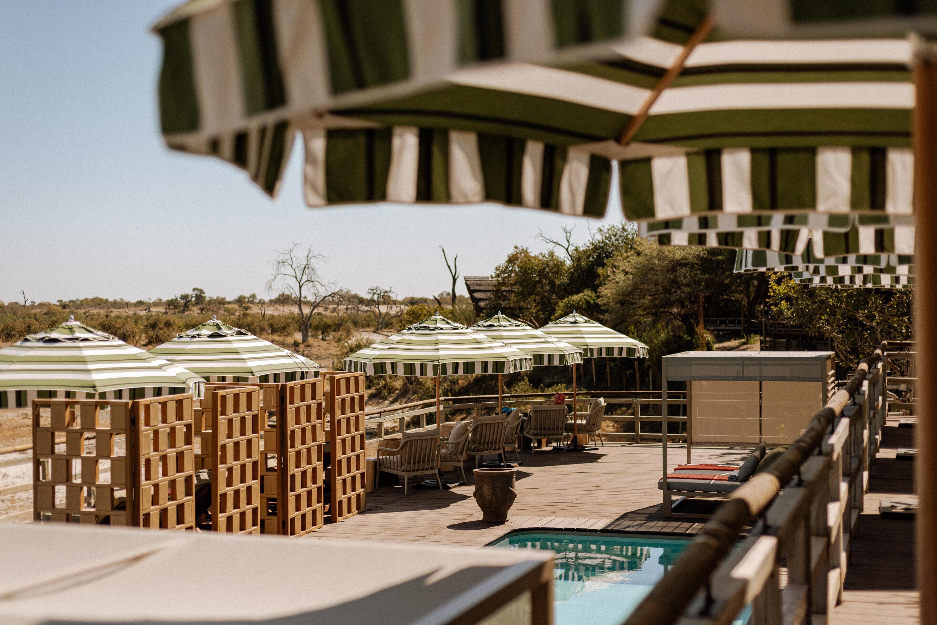 Una piscina al aire libre, sombrillas, sillones reclinables de piscina