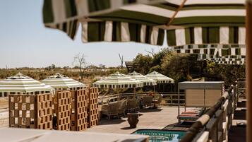 Una piscina al aire libre, sombrillas, sillones reclinables de piscina