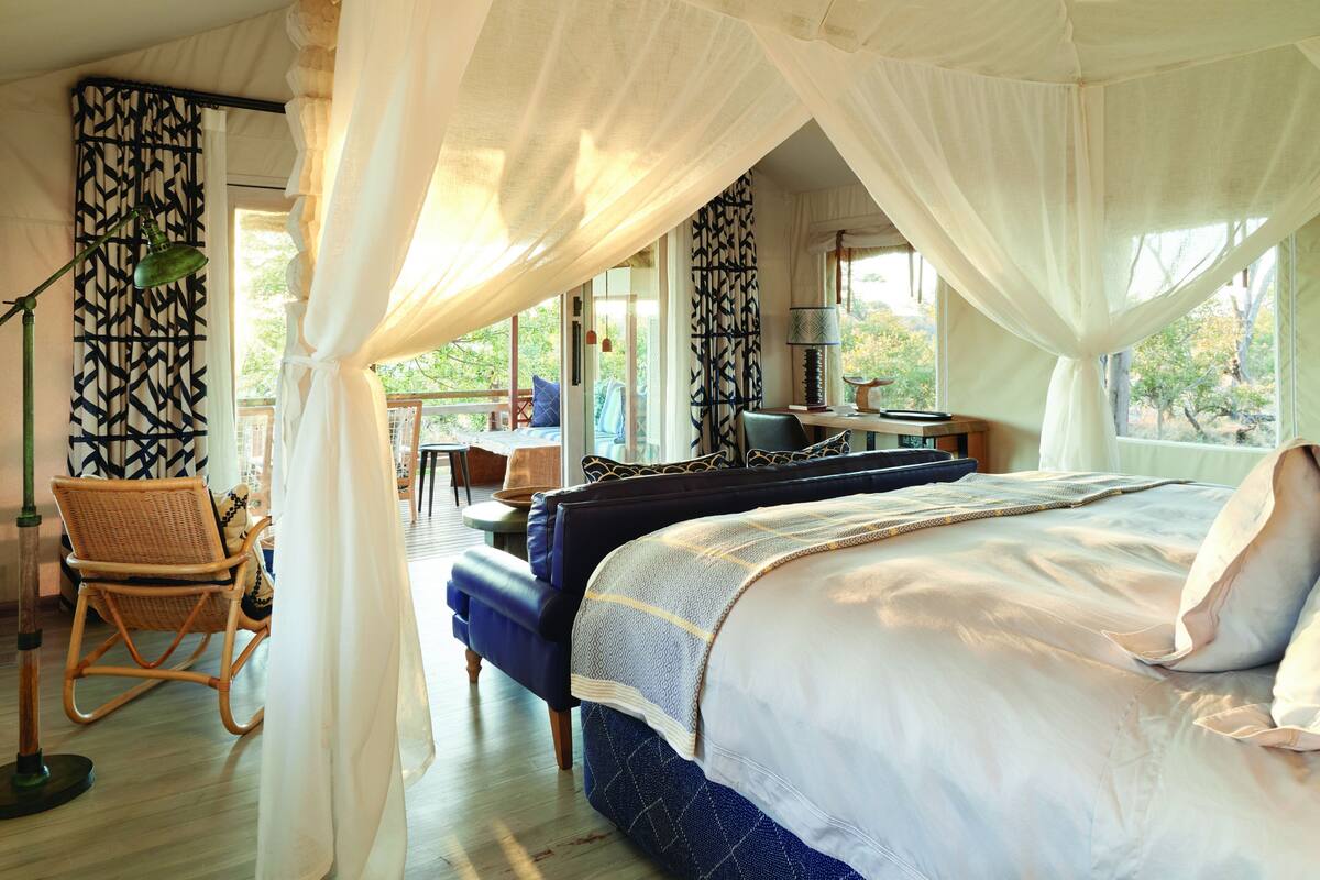 A bedroom with a canopy bed, a desk, and a chair.